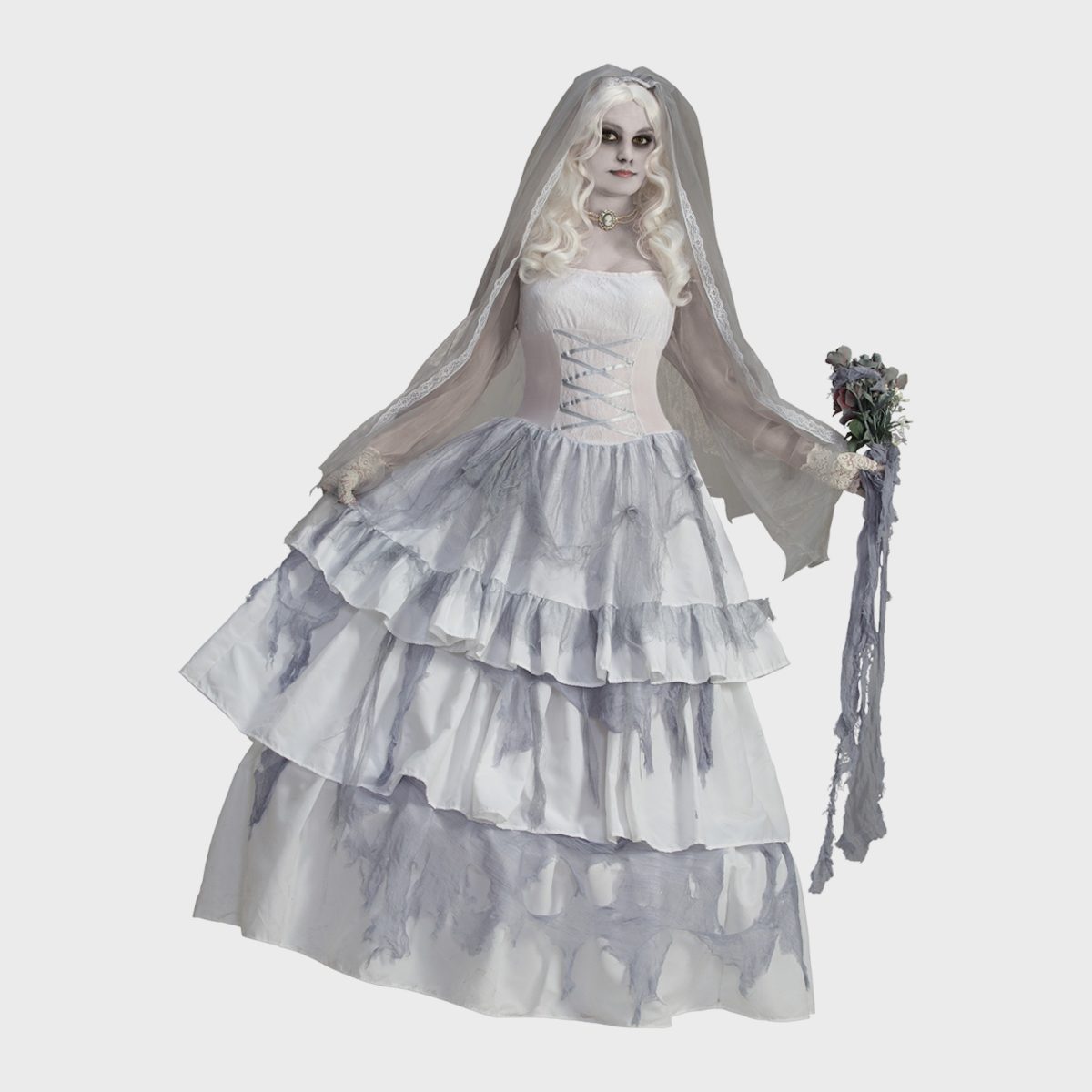 A woman dressed as a ghostly bride holds a tattered bouquet, standing against a plain background, with a layered white and gray dress.