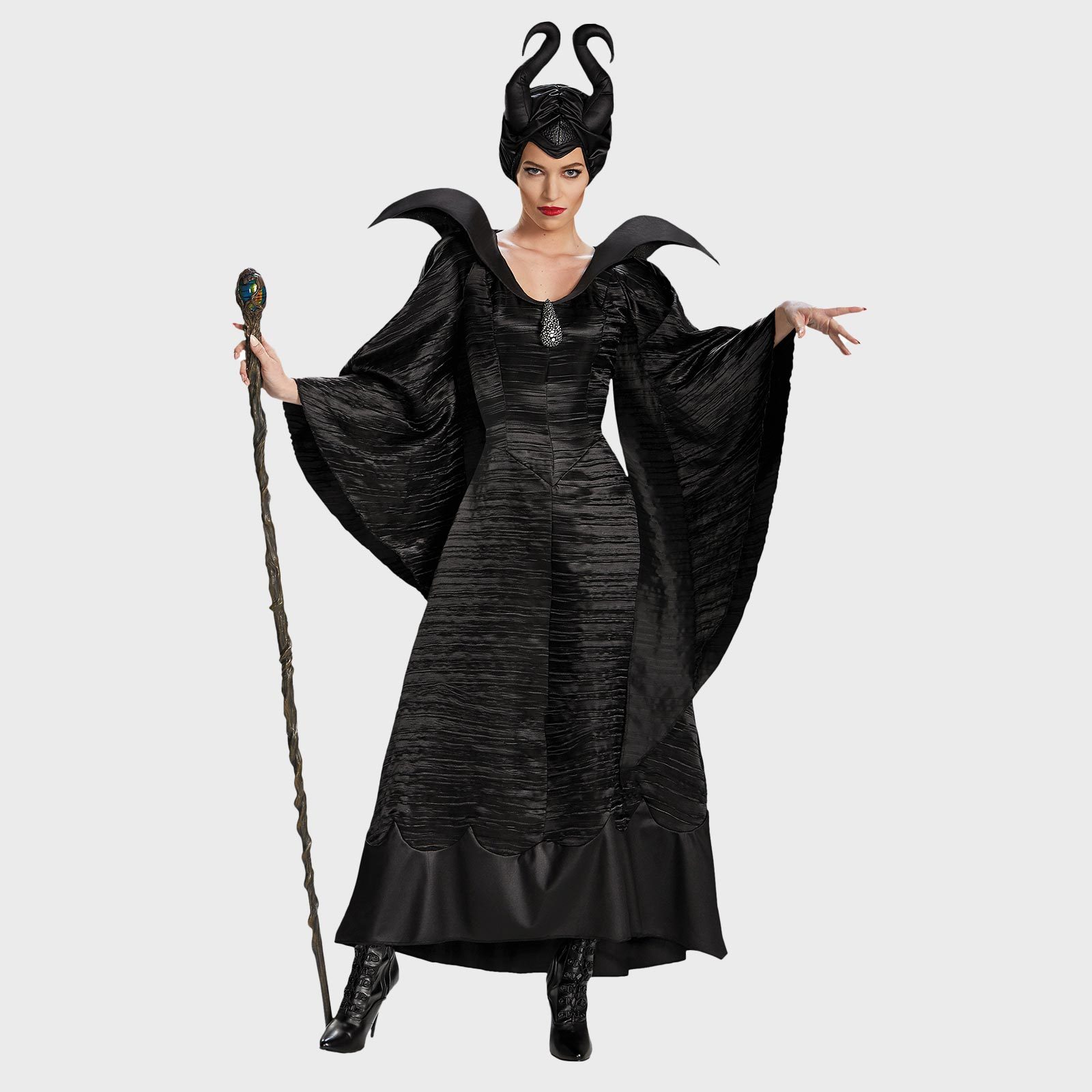 A woman in a black, horned costume holds a twisted staff, posing with an outstretched hand; set against a plain background.