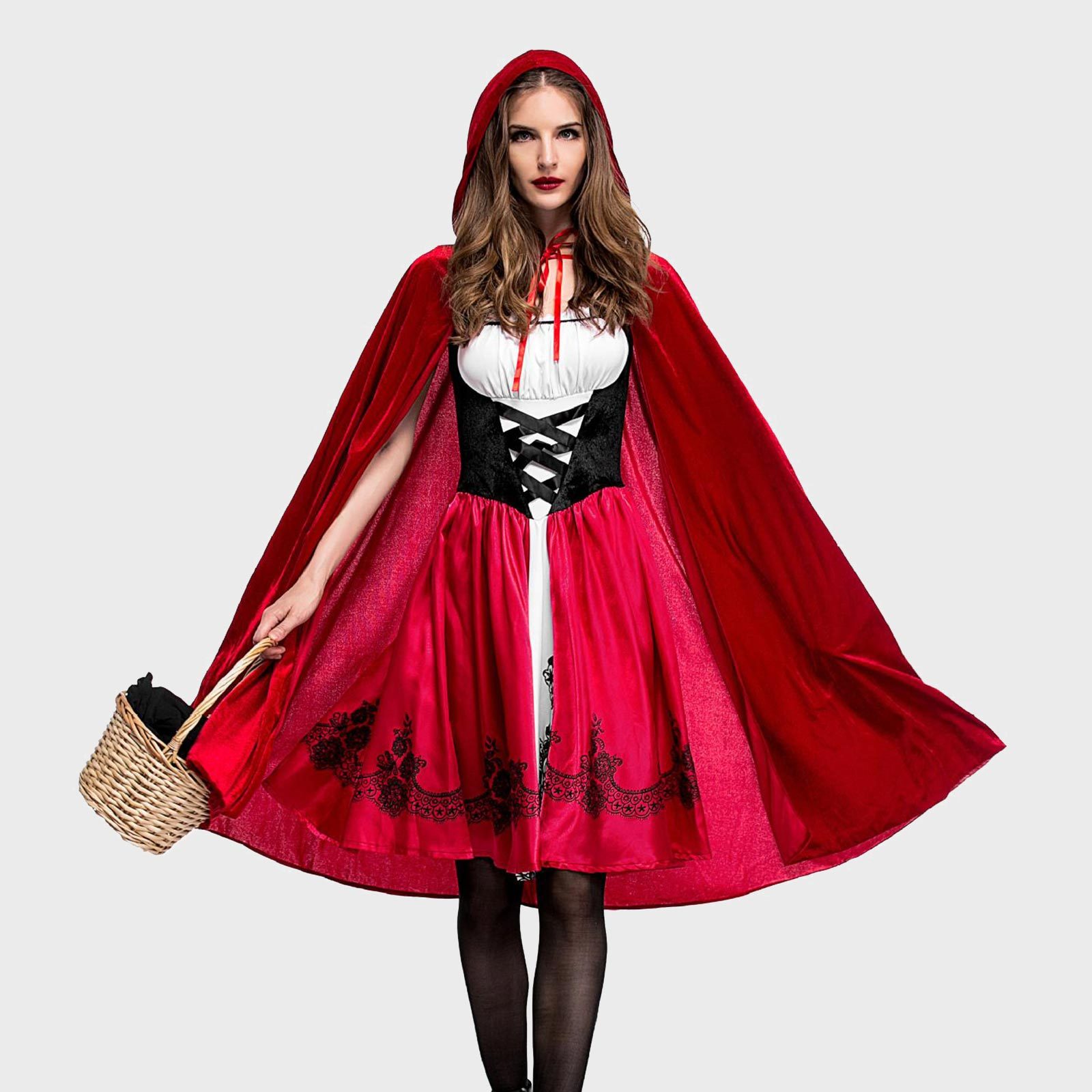 A person wears a red cape and dress, holding a woven basket, against a plain gray background.