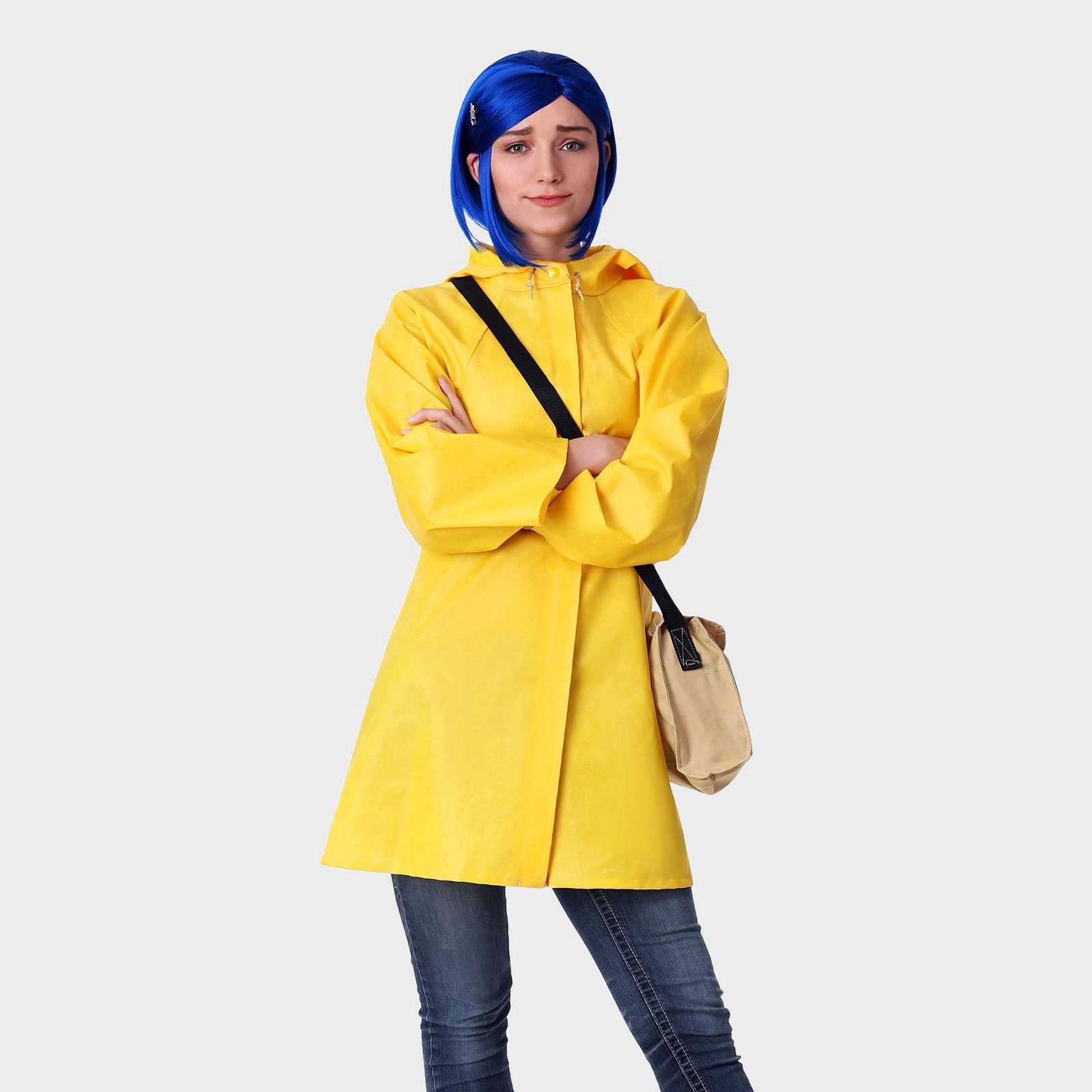 Person stands wearing a bright yellow raincoat and blue wig, arms crossed, with a beige bag; set against a plain gray background.