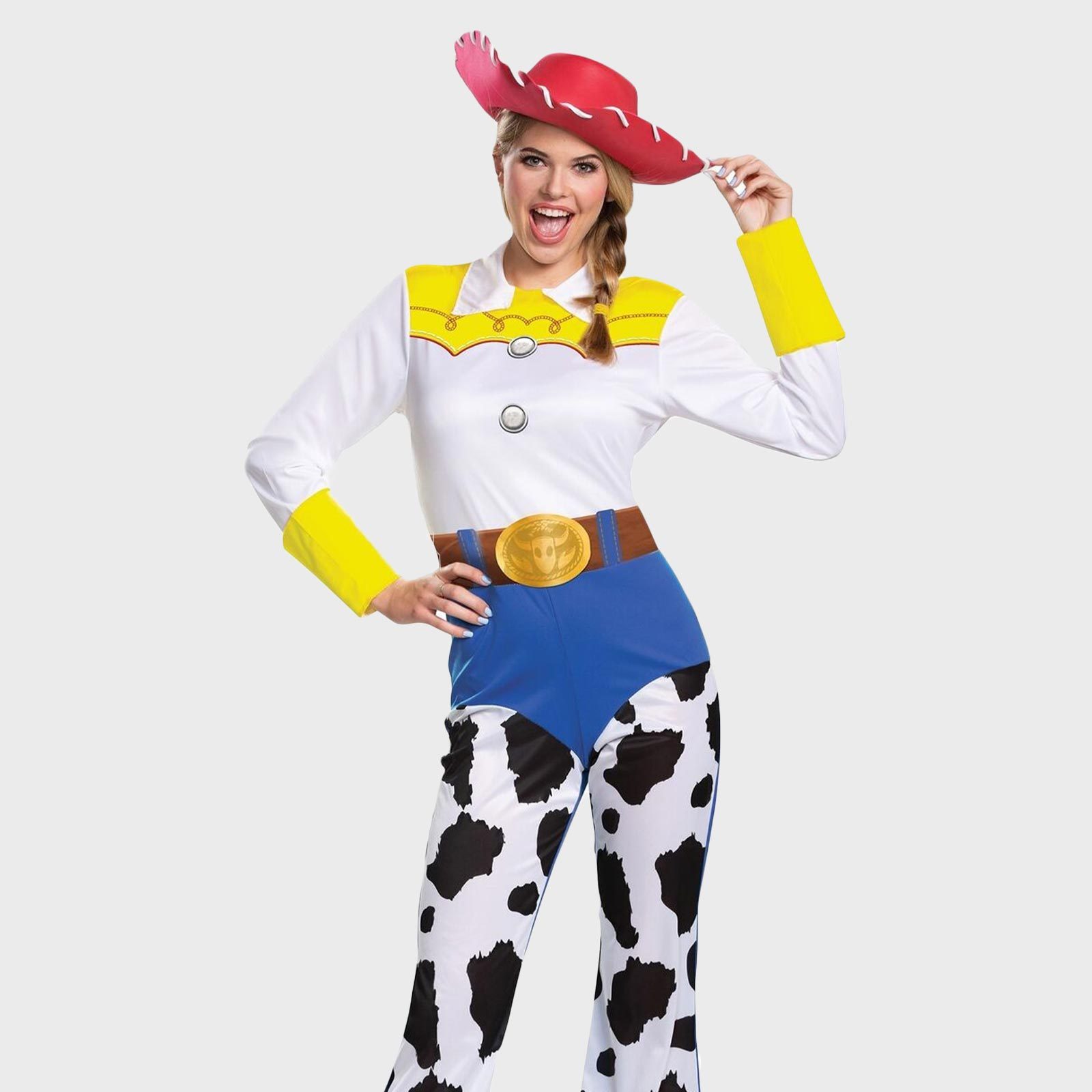 Person wears a cowgirl costume, tipping a red hat, with yellow cuffs and cow-print chaps, smiling against a plain background.