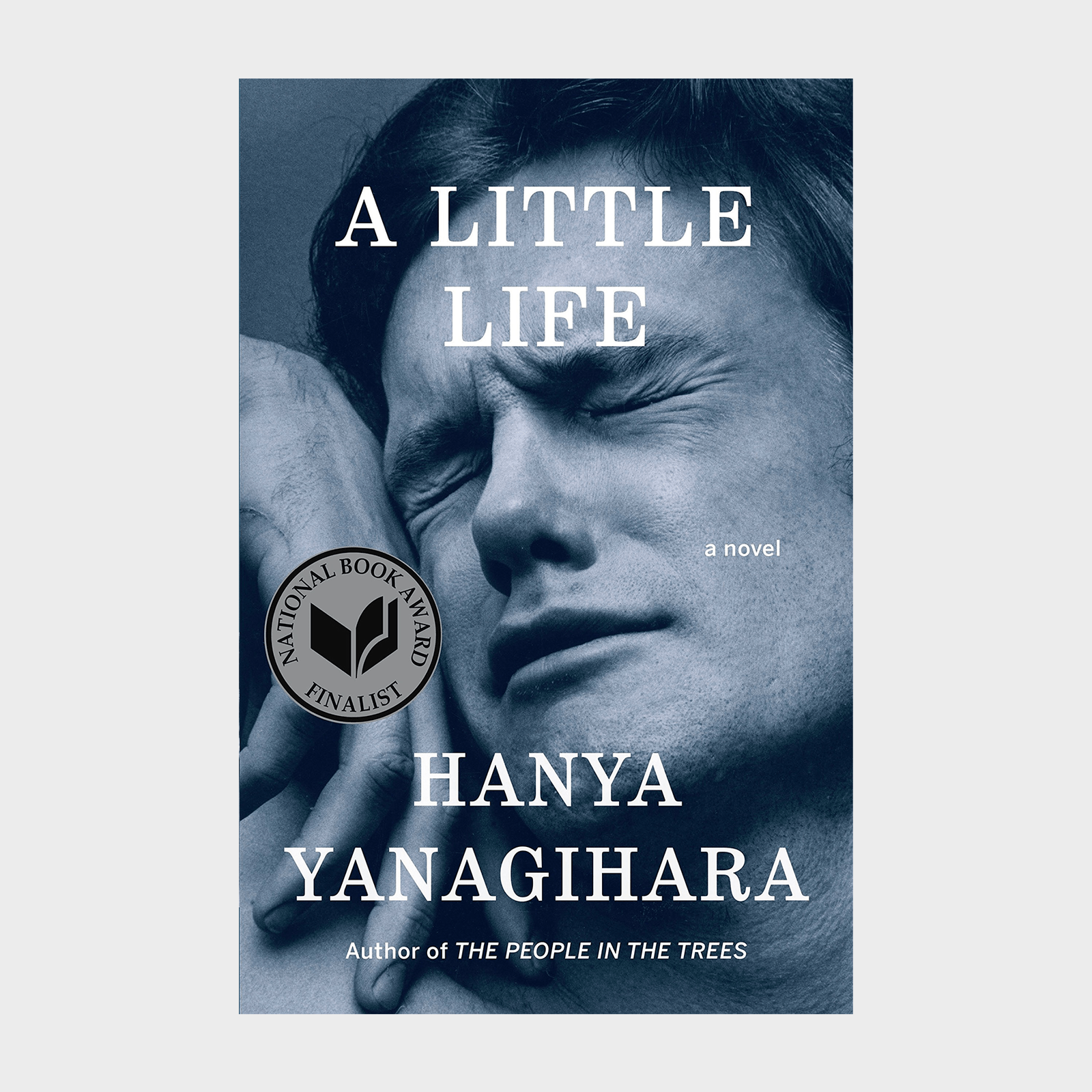 Black-and-white close-up of a person grimacing, eyes closed. Book titled "A Little Life," author Hanya Yanagihara, National Book Award finalist sticker.