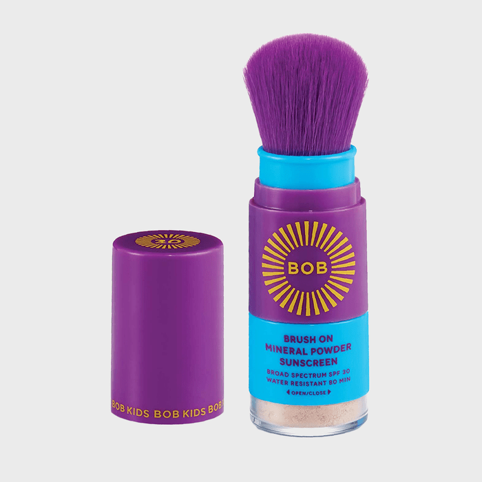 Purple brush dispenses mineral powder sunscreen, labeled 