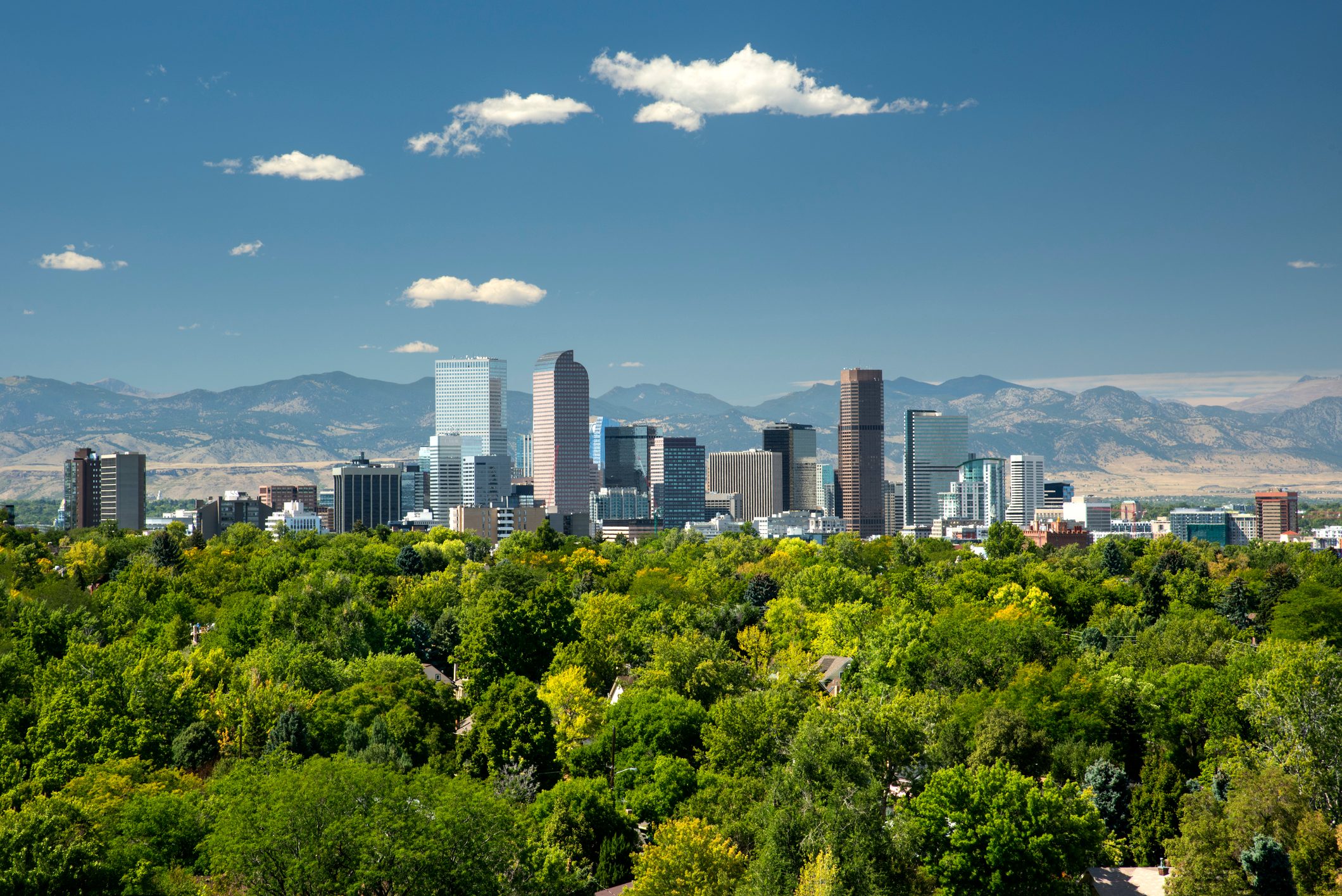 The towering high rises of Denver's downtown sit between the Front Range of the Rocky Mountains to the west and the tree lined neighborhoods and parks of the city to the east.