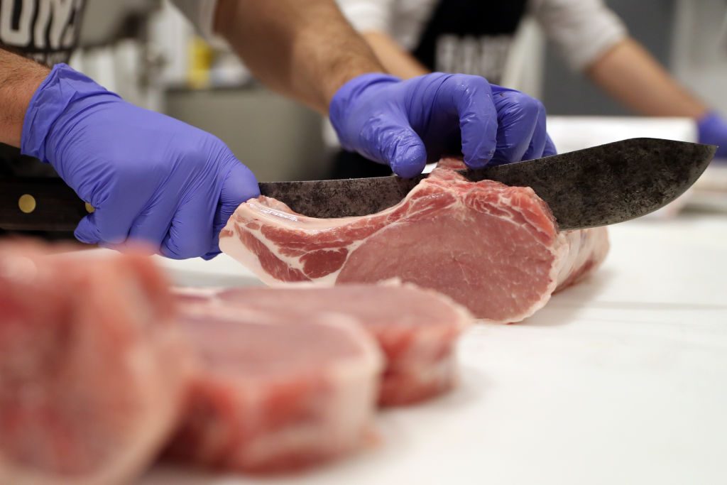 a butcher cuts a piece of meat at the grocery store