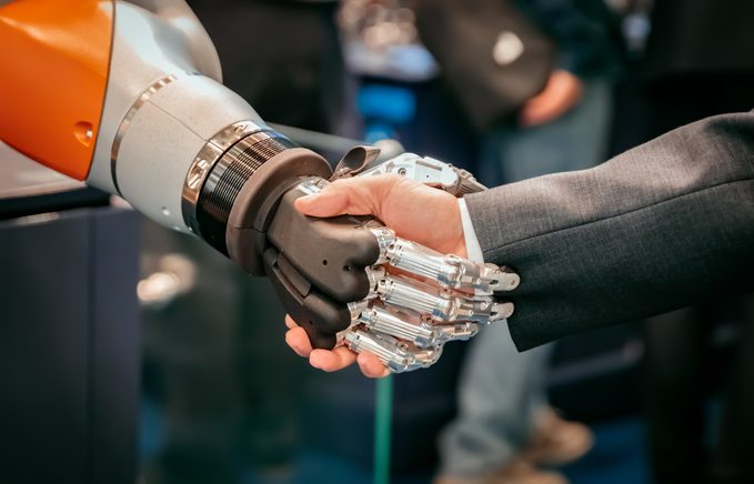 Hand of a businessman shaking hands with a Android robot.