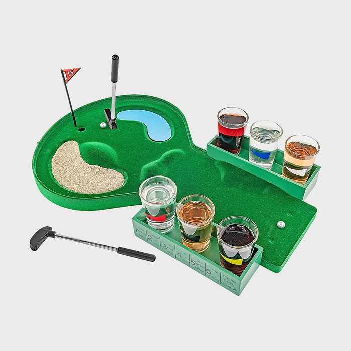 Miniature golf course holds a putter and six shot glasses, surrounded by sand trap and water hazard, on a tabletop green.