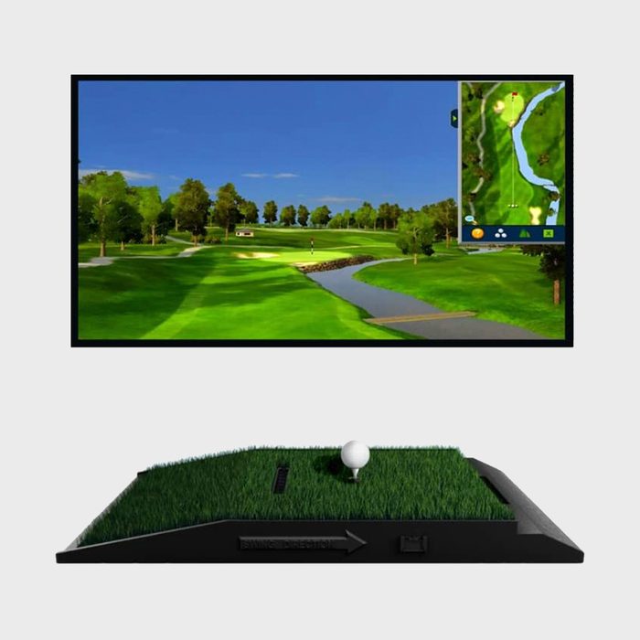 Golf ball sits on a mat; a screen displays a virtual golf course with lush greenery and a pond, map overlay included.
