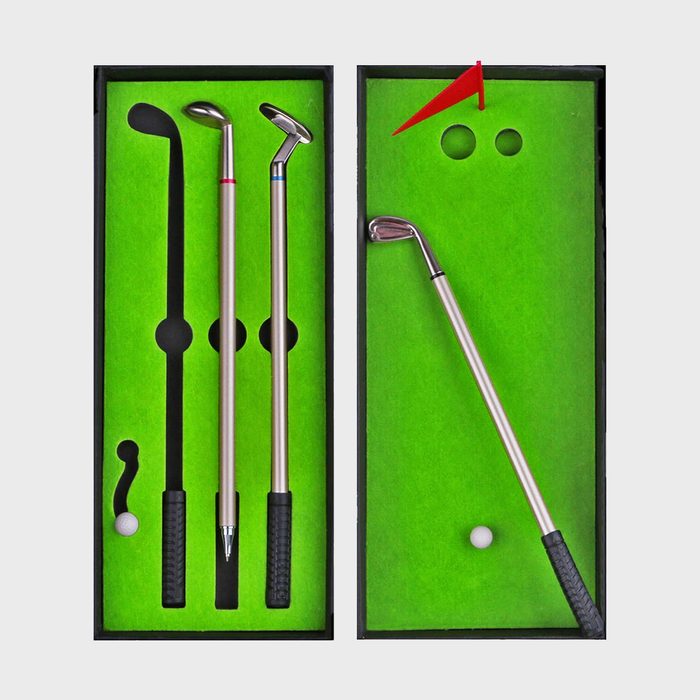 Mini golf set rests arranged inside a box with green felt, featuring clubs, a red flag, and golf balls.