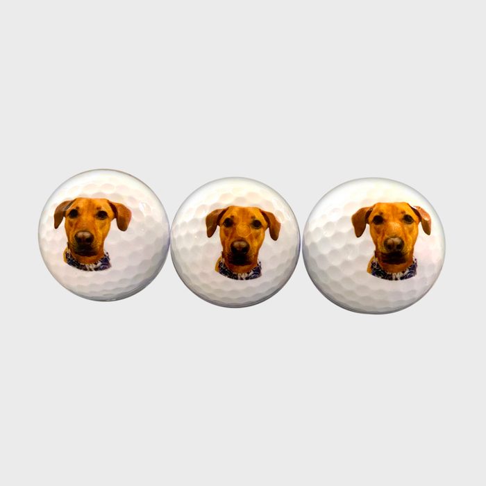 Golf balls display a dog's face, arranged side by side, against a plain background.