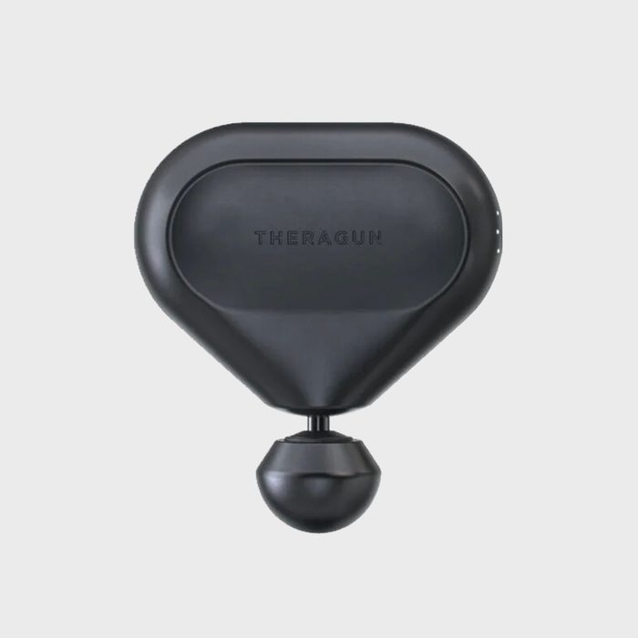 A black massage gun with a rounded handle and ball attachment sits against a plain background. 