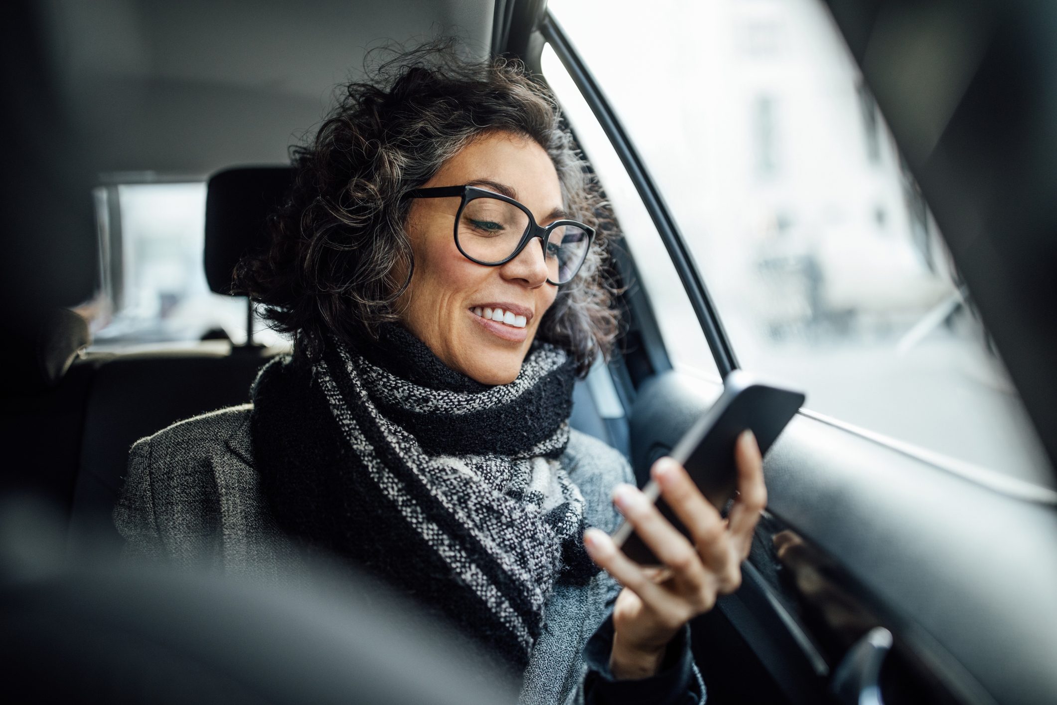 woman using phone while traveling by a taxi