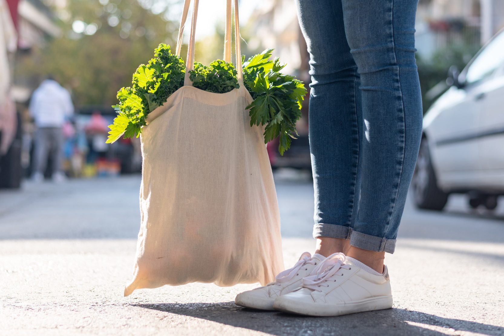 Low angle view at female with reusable shopping bag with vegetables inside. Eco friendly lifestyle