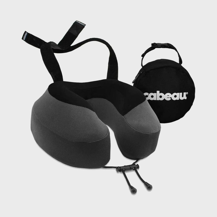 Neck pillow rests on a gray surface, accompanied by a round black travel bag labeled 