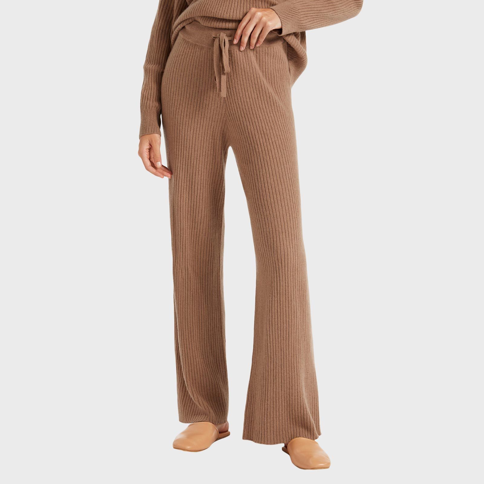 Tan ribbed knit pants hang loosely, paired with matching top and beige slippers, set against a plain white background.