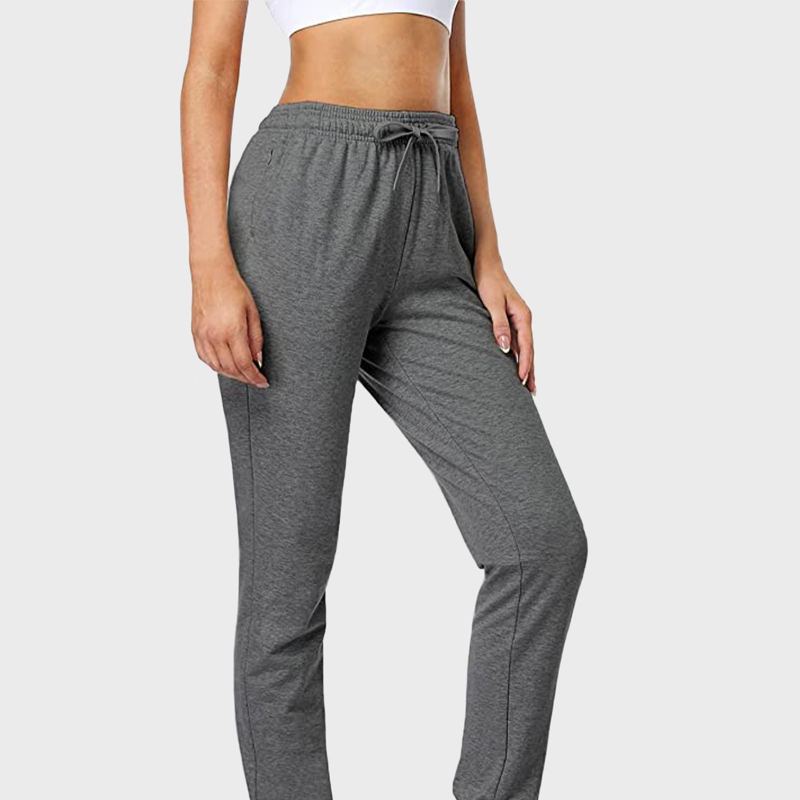 Gray sweatpants hang relaxed on a standing person, paired with a white cropped shirt, set against a plain light background.