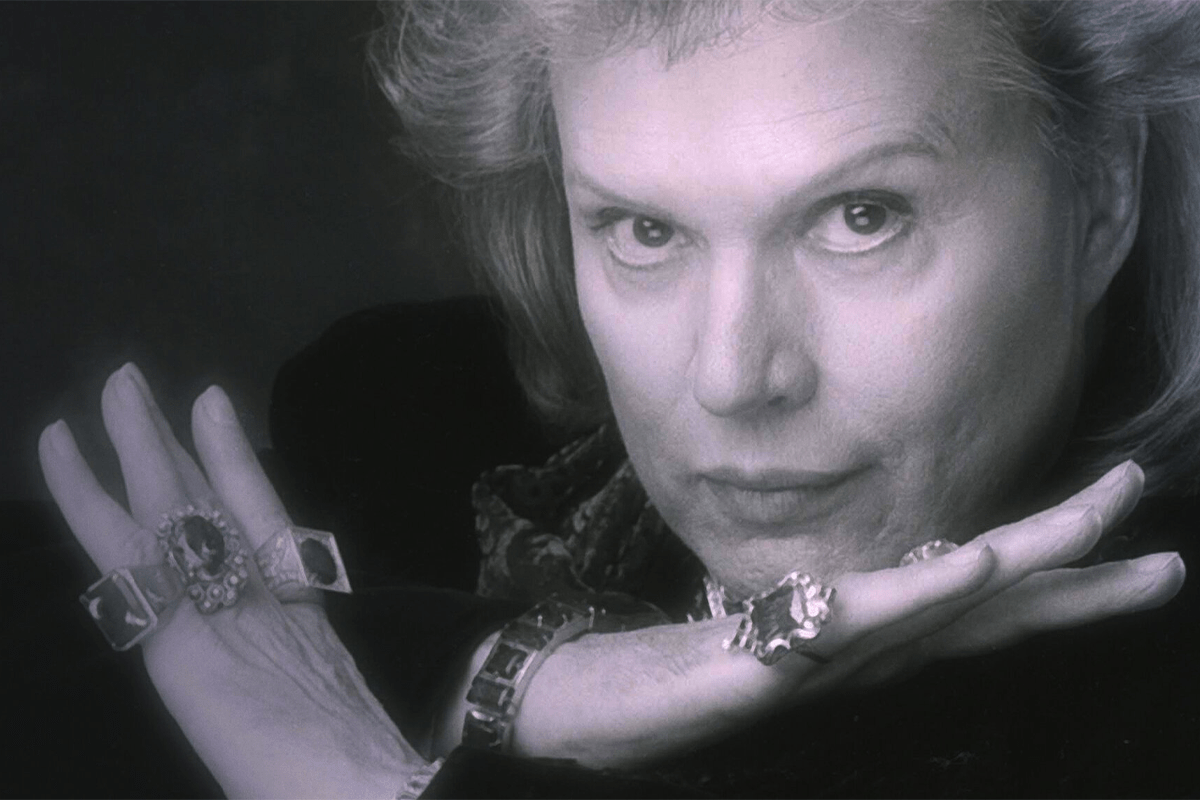 Person displaying rings on fingers, gazing confidently, against a dark background.