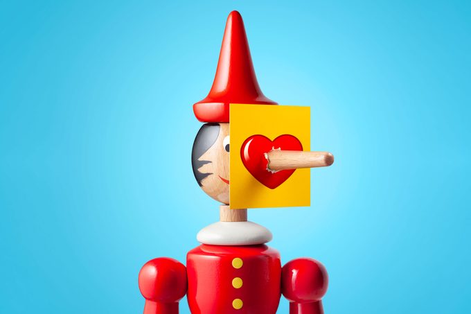 Pinocchio figurine with nose breaking through a picture of a heart