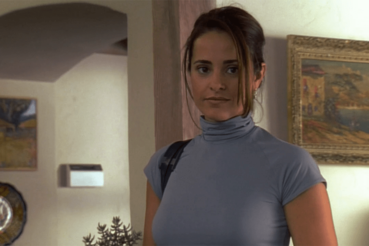 Person standing, wearing a turtleneck, in a room with artwork on the walls.