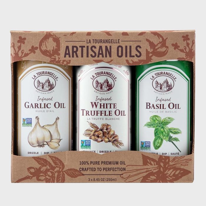 Bottles display flavored artisan oils, featuring garlic, white truffle, and basil. They are packaged together in a decorated box with textual branding.