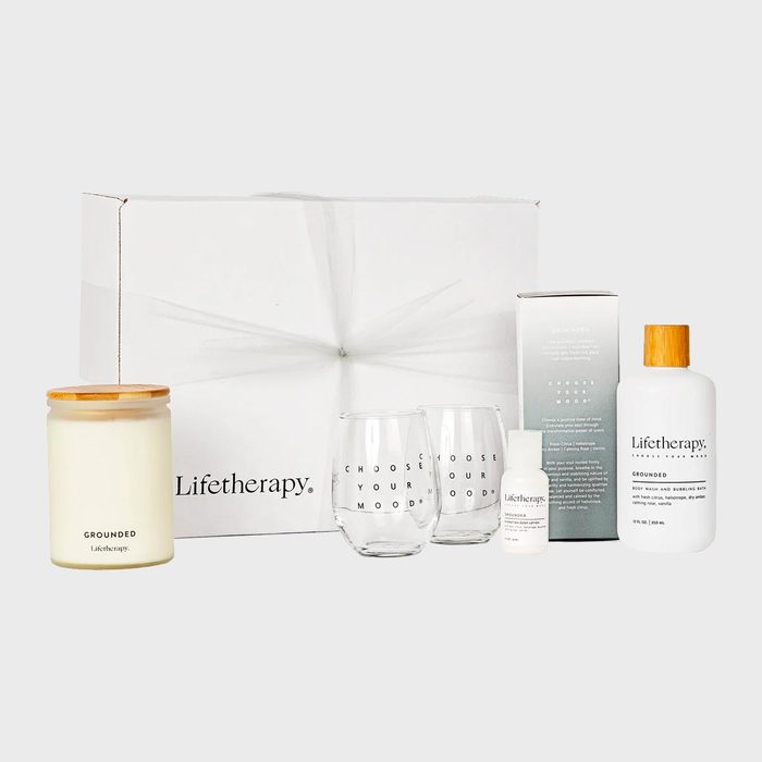 Gift box contains candle, glasses, and bottles; arranged on a white surface showing 