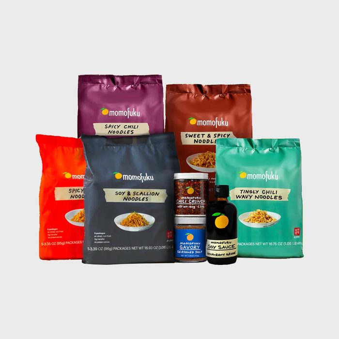 Various Momofuku noodle packages and condiments are displayed together against a plain backdrop, featuring flavors like Spicy Chili and Tingly Chili Wavy.