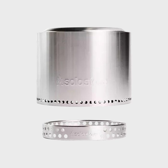 Stainless steel stove and ring align, suspended in air, against plain gray background. Engraved text: 