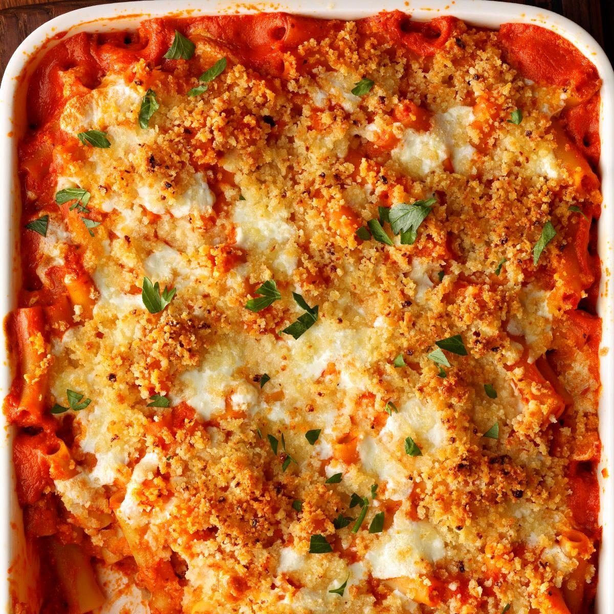 A baked pasta dish, with golden breadcrumbs and melted cheese, sits in a white rectangular dish, garnished with parsley.