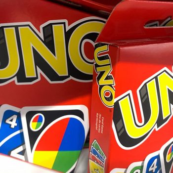 UNO card game box, unopened, sits on a shelf, with vibrant color cards displayed on the packaging.