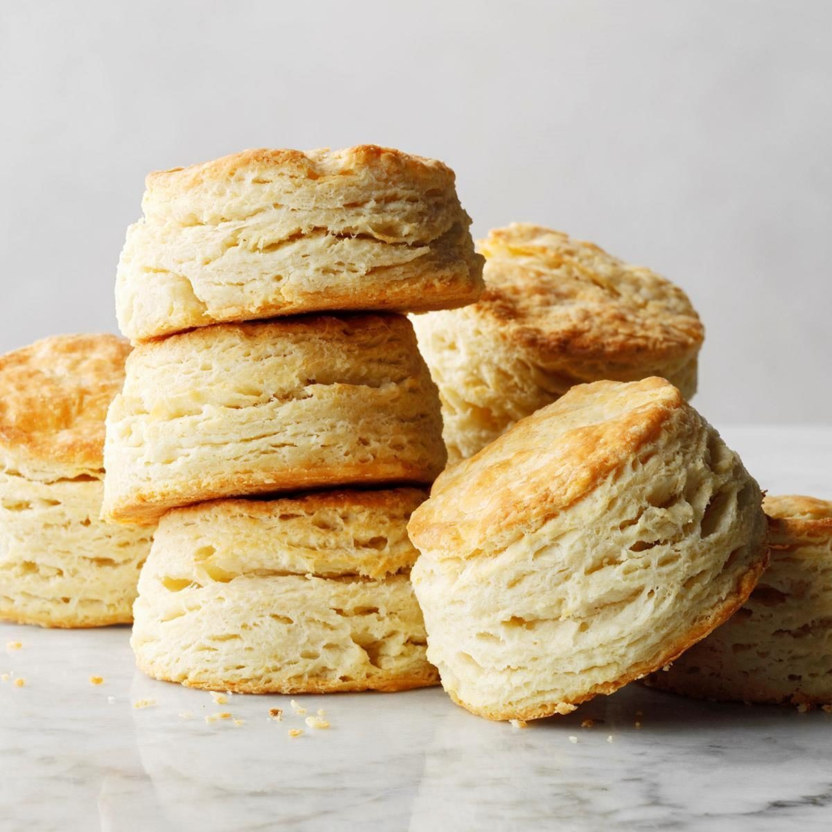 Golden, flaky biscuits stacked on a marble surface, creating a warm and inviting culinary scene.