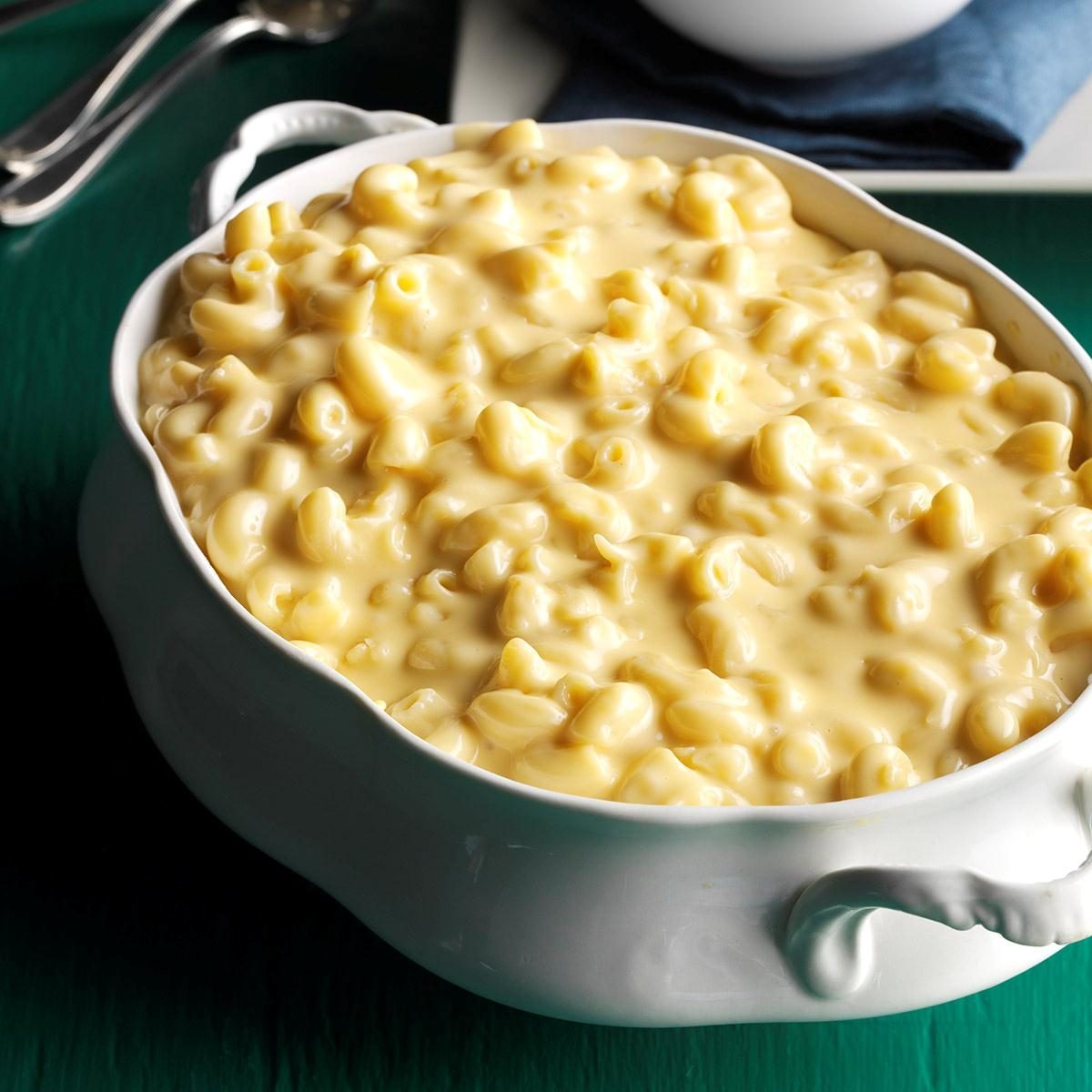 Macaroni sits in creamy cheese sauce within a white casserole dish on a green table.