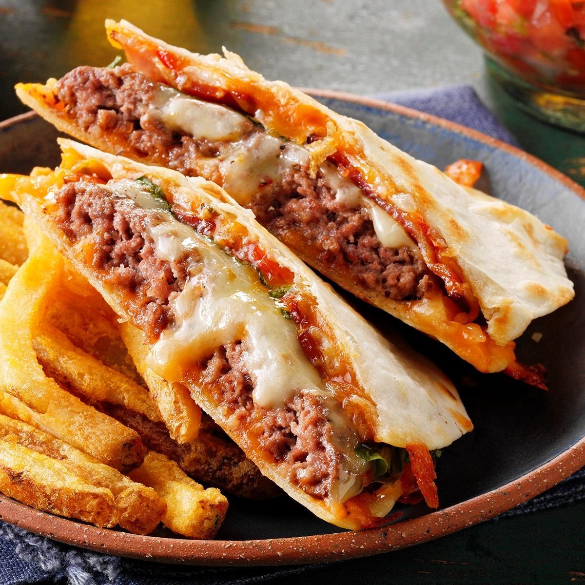 Quesadilla cross-sections reveal melted cheese and beef filling, placed on a plate next to golden, crispy fries.