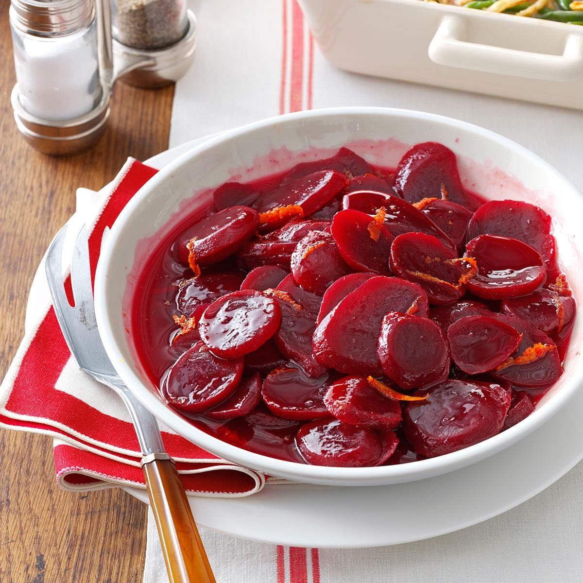 Bowl holding sliced beets rests on a white and red napkin, accompanied by a knife, with salt and pepper shakers nearby.
