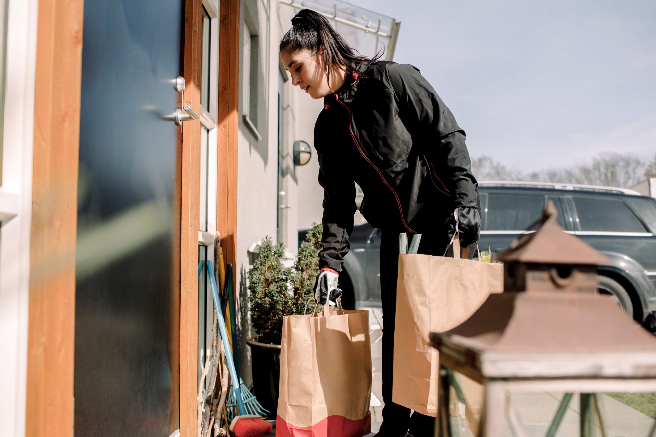Young delivery woman delivering groceries at house