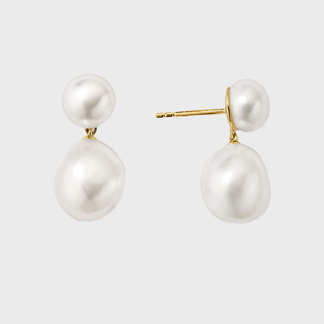 Pearl earrings, featuring a smaller pearl on top, larger below, connected by gold, against a plain light gray background.