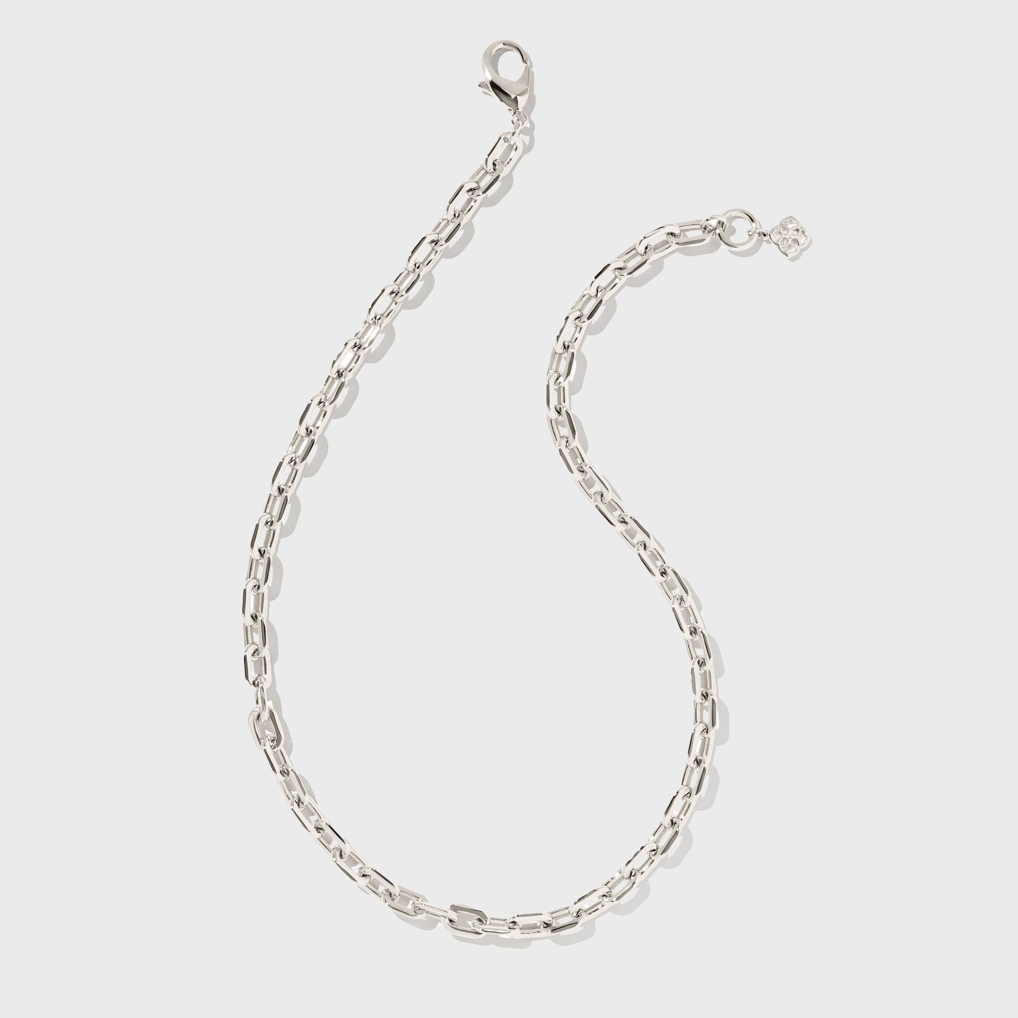 Silver chain lies flat with a small pendant attached, against a plain white background.
