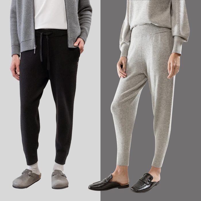 Two people wearing casual sweaters and joggers stand side-by-side; one wears black joggers, gray sweater, slippers, while the other wears gray joggers, sweater, loafers.