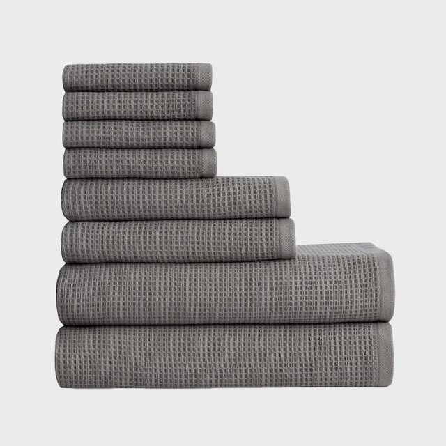 Gray waffle-knit towels neatly stacked in a pyramid shape against a plain white background.