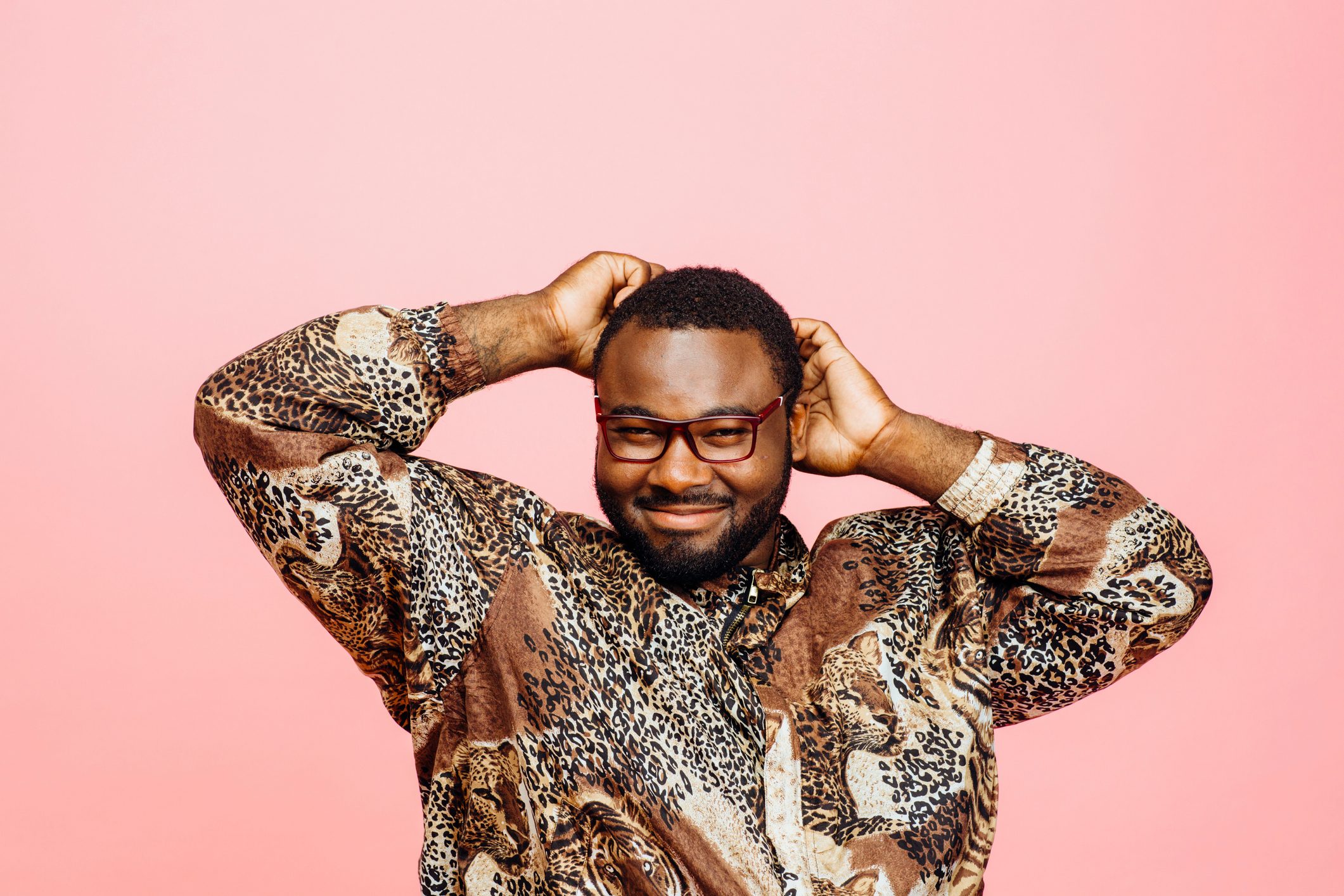 Portrait of a sweet smiling man in leopard print shirt and arms up