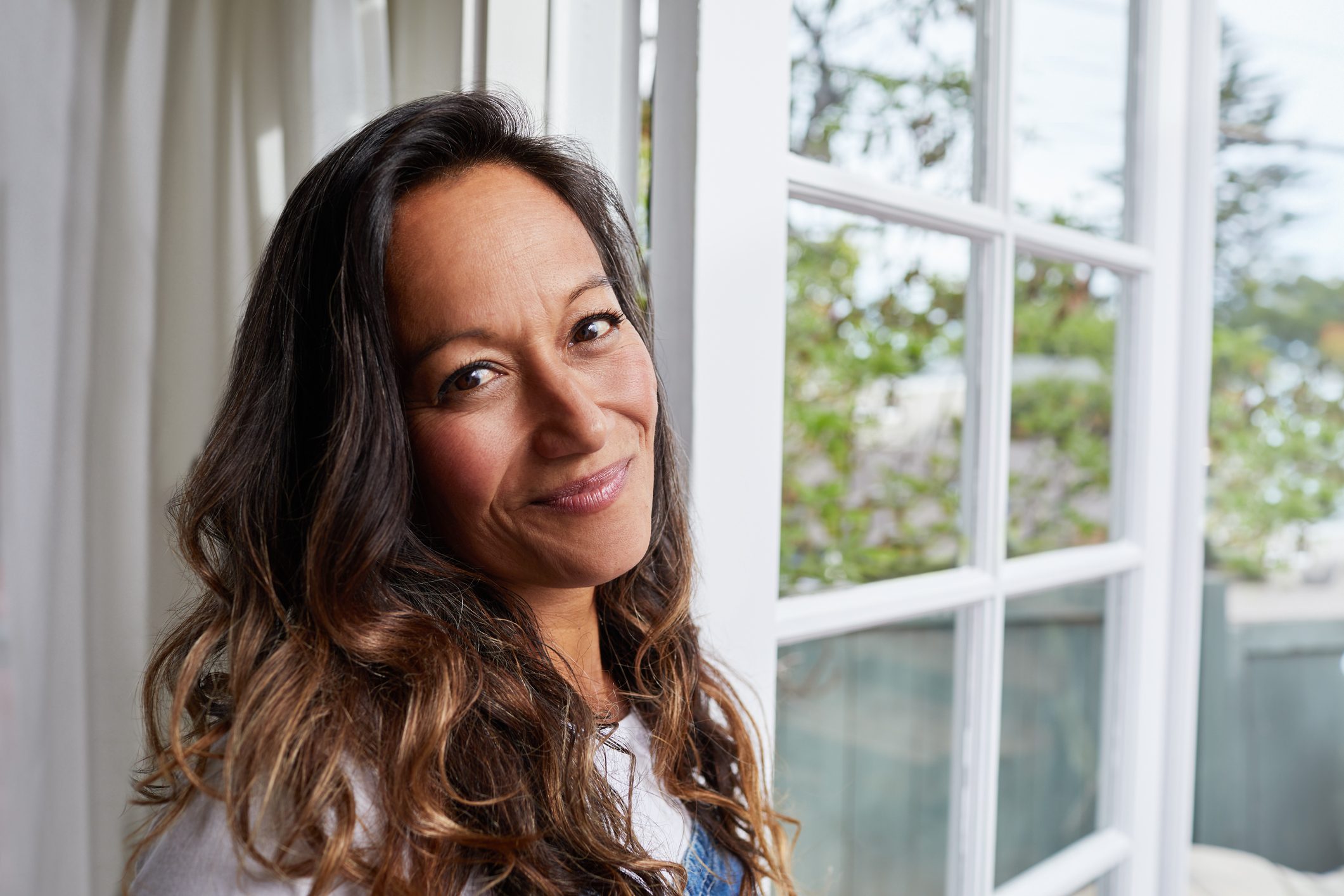 Mature woman smiling while standing by her patio doors