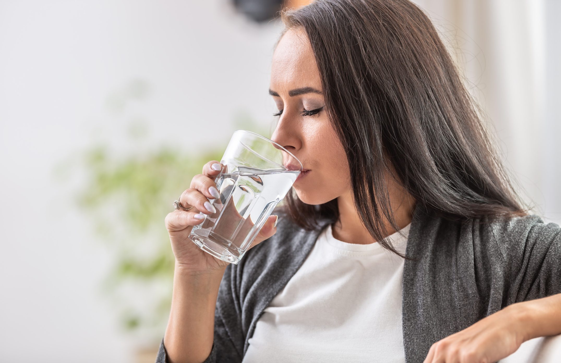 Female drinks water from a glass.
