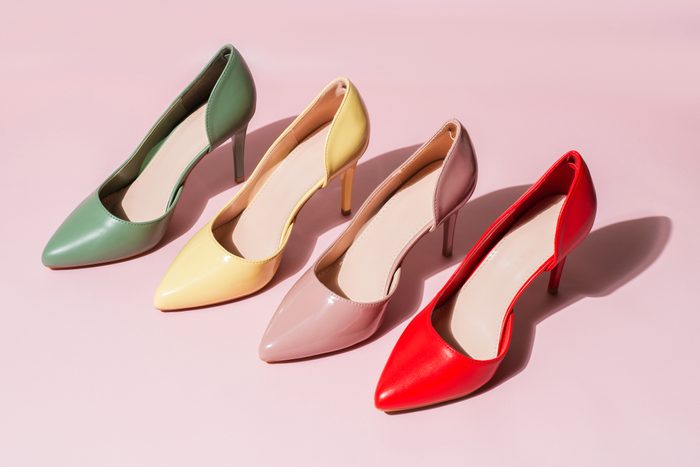 Multicolored womens shoes stand in a row on vinyl pink background