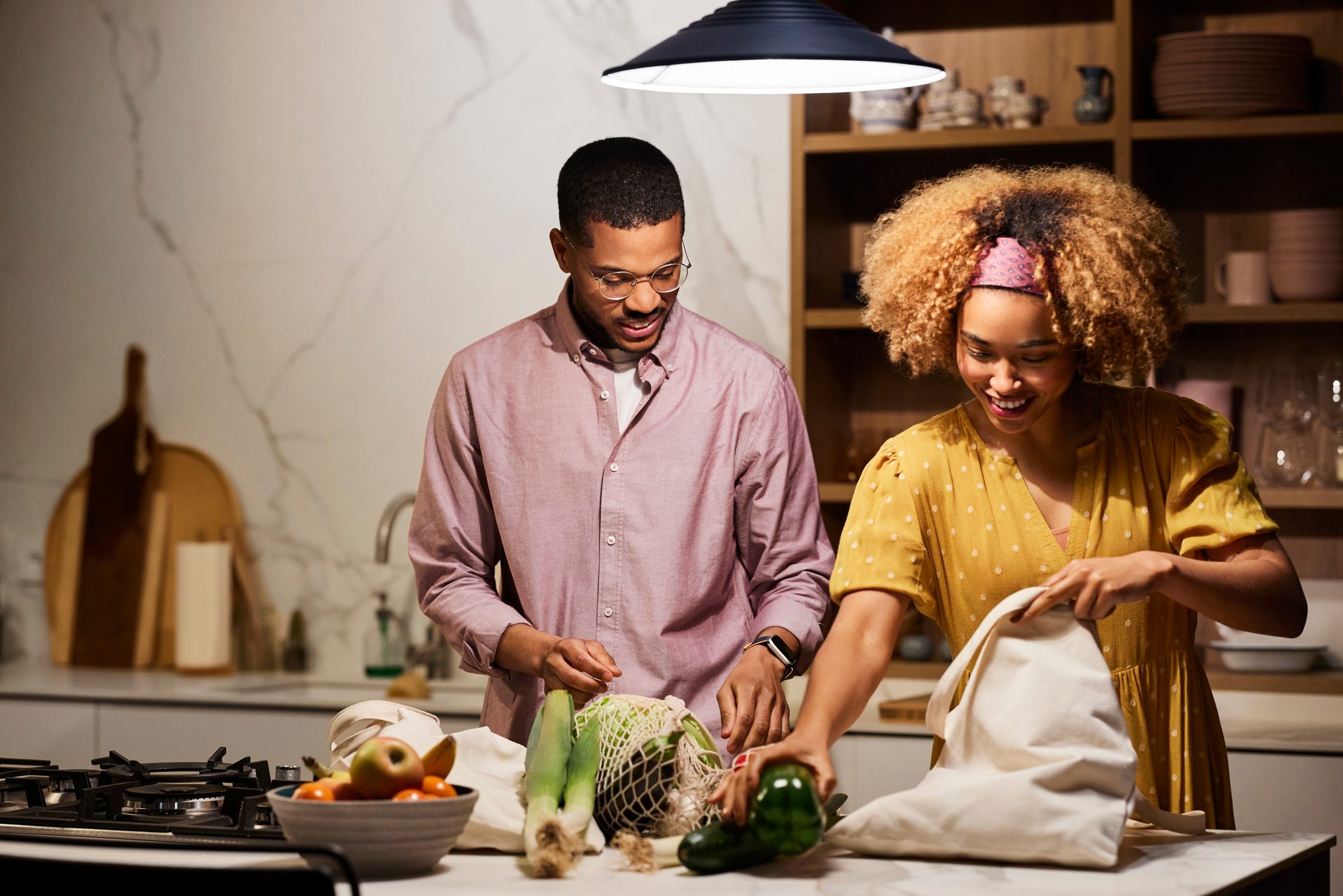 Young Couple Unpacking Vegetables In Kitchen