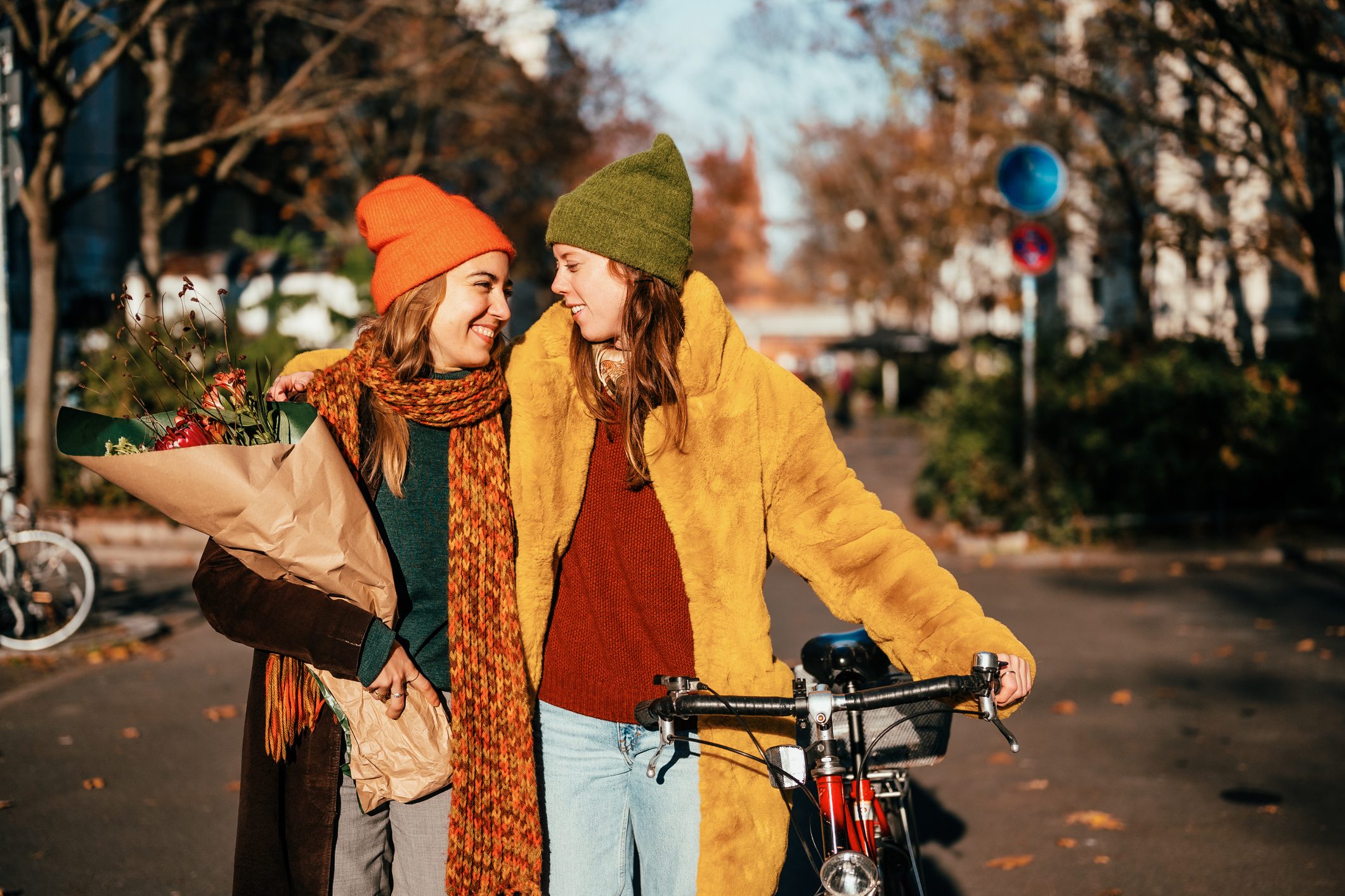 Two women on bikes on a sunny street