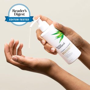 Hands dispense liquid from a white pump bottle labeled 