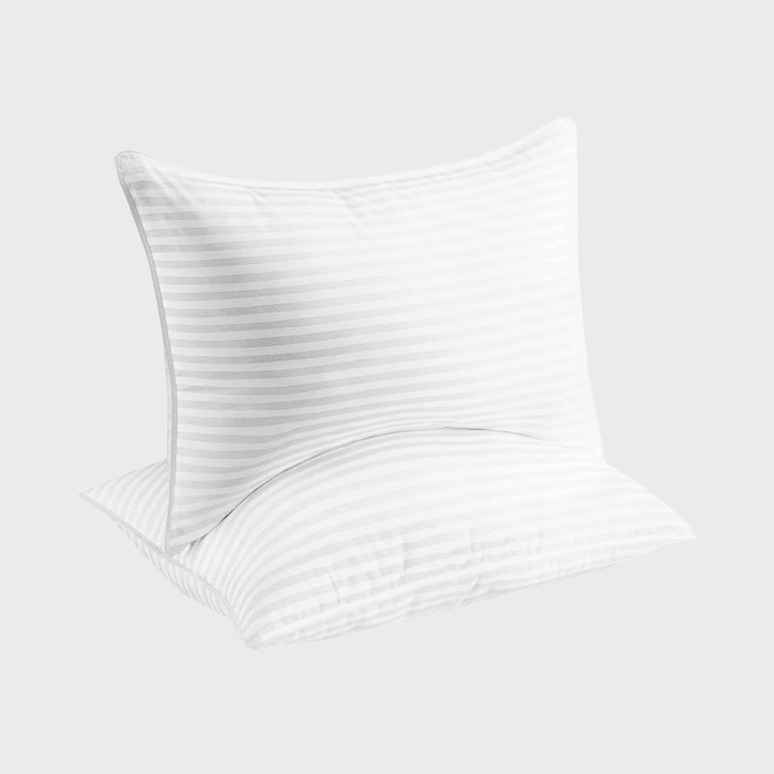 Two white pillows rest together, featuring subtle horizontal stripes, against a plain light gray background.