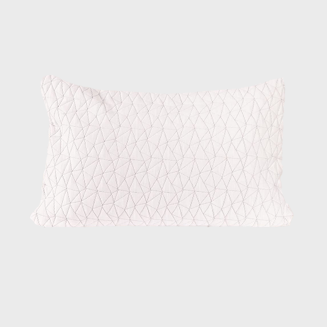 Quilted pillow rests quietly, displaying geometric stitching design on a plain light gray background.