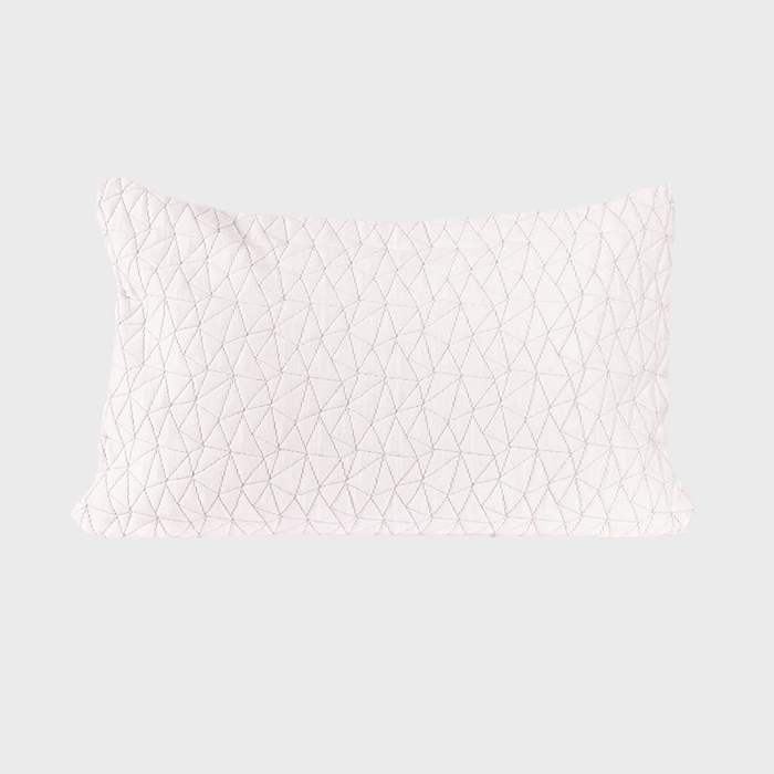 Quilted pillow rests quietly, displaying geometric stitching design on a plain light gray background.