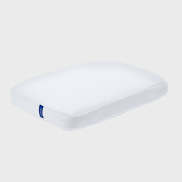 White pillow, resting on a flat surface, with a blue label on the side against a plain gray background.