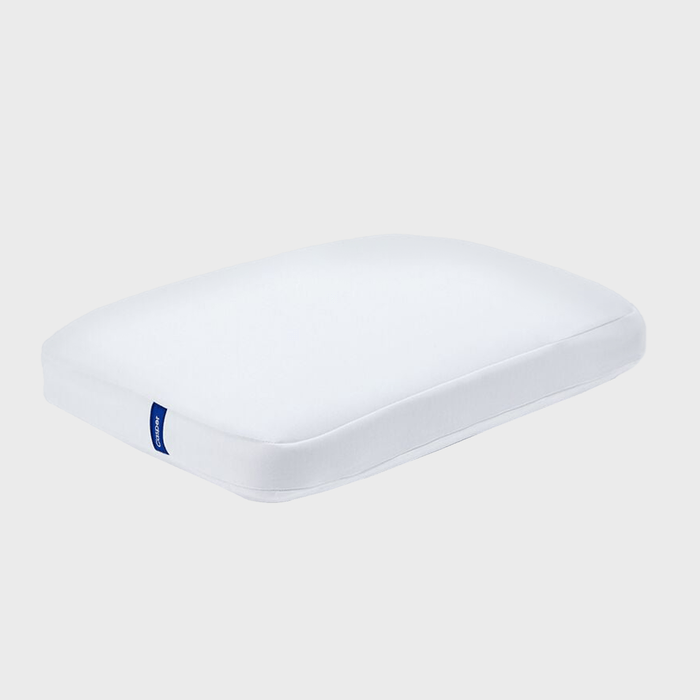 White pillow, resting on a flat surface, with a blue label on the side against a plain gray background.